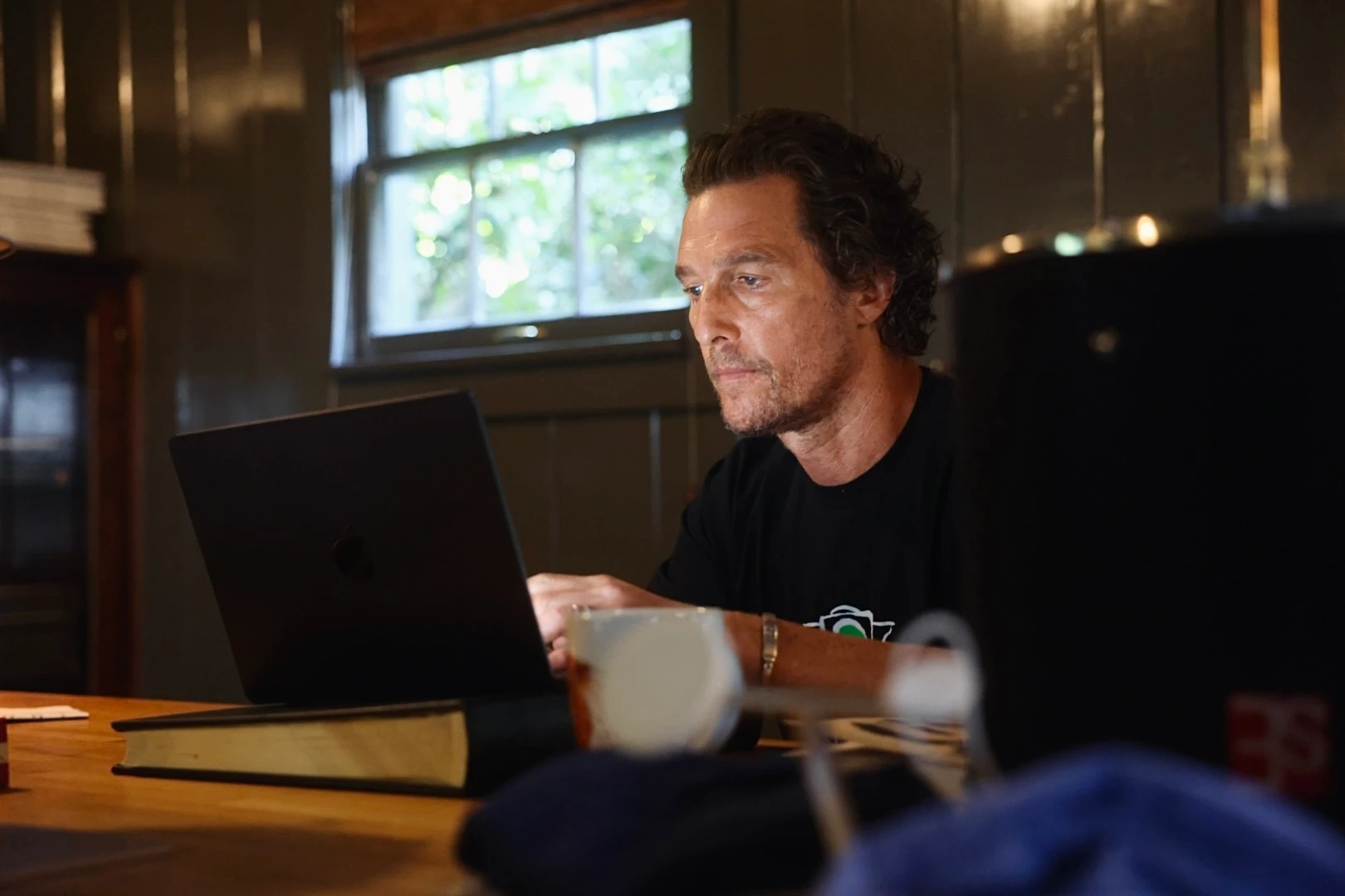 Matthewe McConaughey sitting at a desk and working on his computer